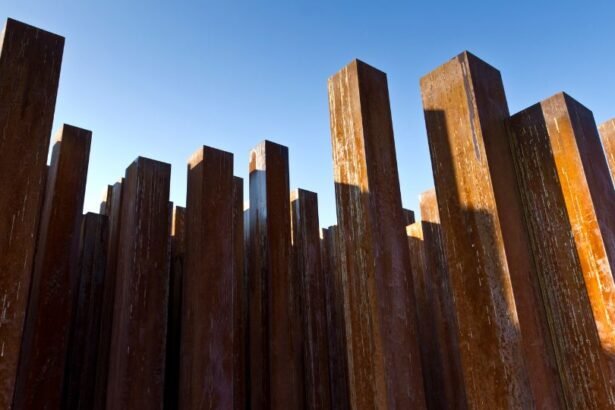 Fém oszlopok sorakoznak egy világos égbolt alatt, rozsdás színnel.