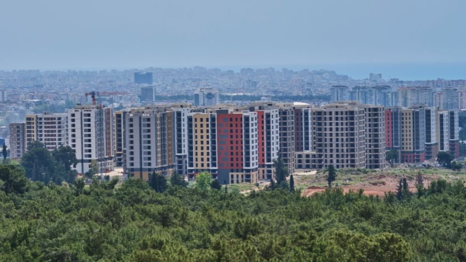 Modern lakóépületek egy városi tájban, háttérben a város sziluettjével.