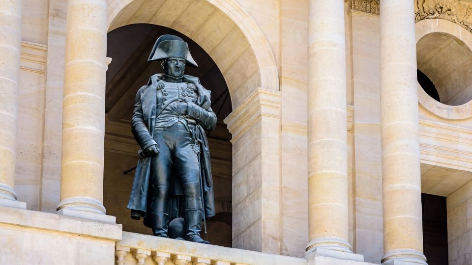 Bonaparte Napóleon szobra egy épület homlokzatán, díszes oszlopok között.