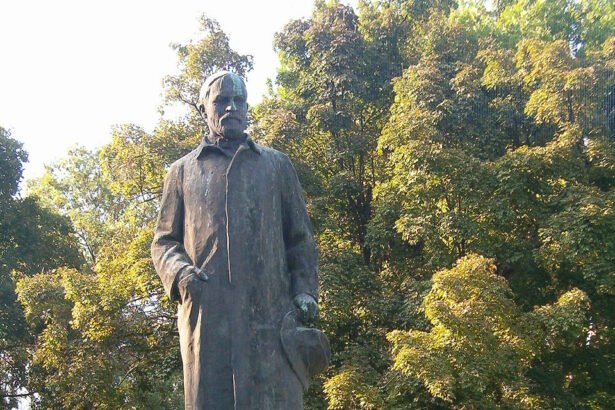 Juhász Gyula szobra egy parkban, zöld fákkal körülvéve.