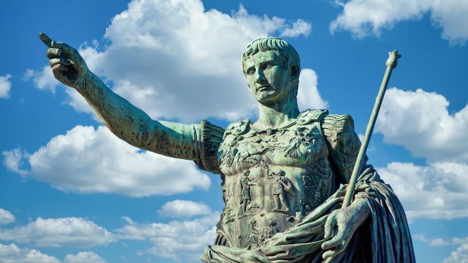 Julius Caesar bronzszobra, amely az égre mutat, háttérben felhős ég.