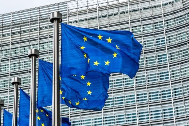 Az Európai Unió zászlói lobognak egy modern épület előtt.