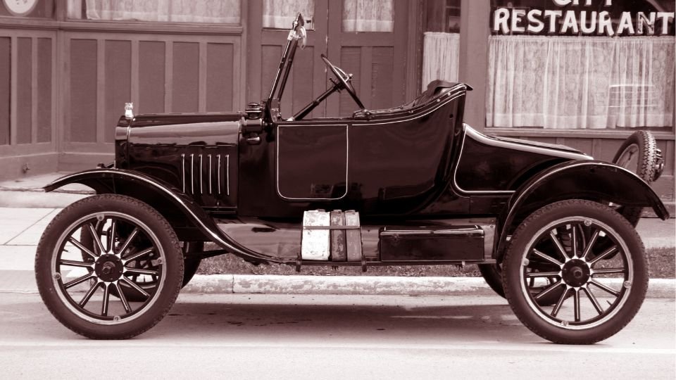 Egy régi, fekete színű autó az utcán, vintage stílusban.