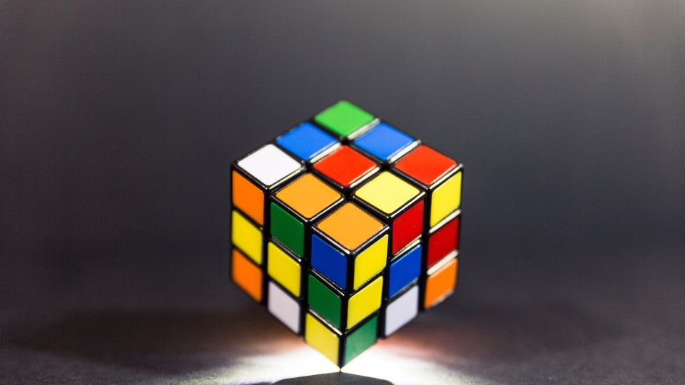 Színes Rubik-kocka sötét háttér előtt, világítással kiemelve