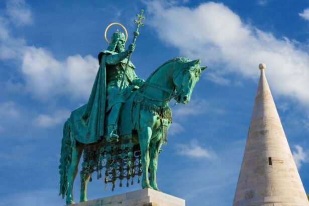 Szent István király bronzszobra, lóháton állva, háttérben kék ég és fehér felhők.