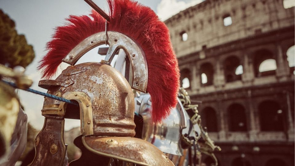 Római gladiátor sisakok sorakoznak a Colosseum előtt, a napfényben ragyognak.