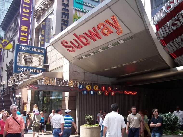 New York metróállomás, emberek a városban a Subway felirat alatt.
